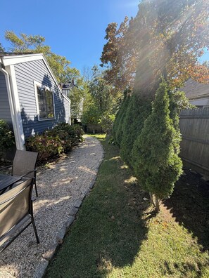 A residential backyard with a gravel path, a wooden deck, and a well-maintained lawn. - Coastal Marblehead Retreat, Minutes to Salem, Beautifully Renovated (Marblehead)
