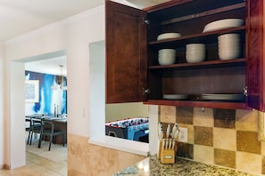 A kitchen with a wooden cabinet containing white bowls and plates, a foosball table, and a knife block on the counter. - Private pool paradise w/ping pong, foosball & outdoor fire pit! (Tempe)