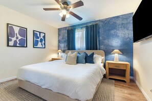 A bedroom with a bed, two bedside tables, a ceiling fan, and artwork on the wall. - Private pool paradise w/ping pong, foosball & outdoor fire pit! (Tempe)