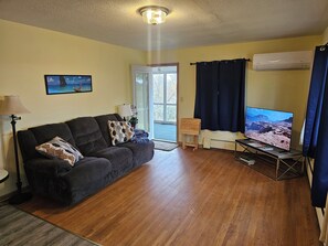 Ein Wohnzimmer mit einer Couch, einem Fernseher und einer Lampe.