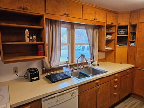 Eine Küche mit Holzausstattung, einer Spüle, einem Toaster und einem Fenster mit Vorhängen.