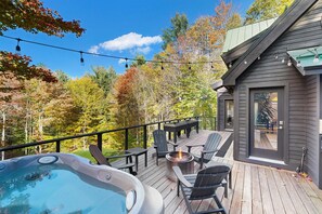 Eine Terrasse mit Sitzgelegenheit, einem Whirlpool und Blick auf ein bewaldetes Gebiet.