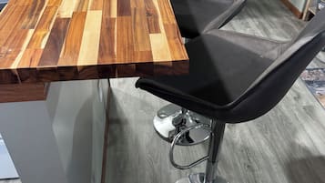 A modern kitchen with a wooden countertop and a black bar stool.