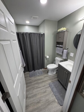 Een badkamer met toilet, wastafel, spiegel en douchegordijn.