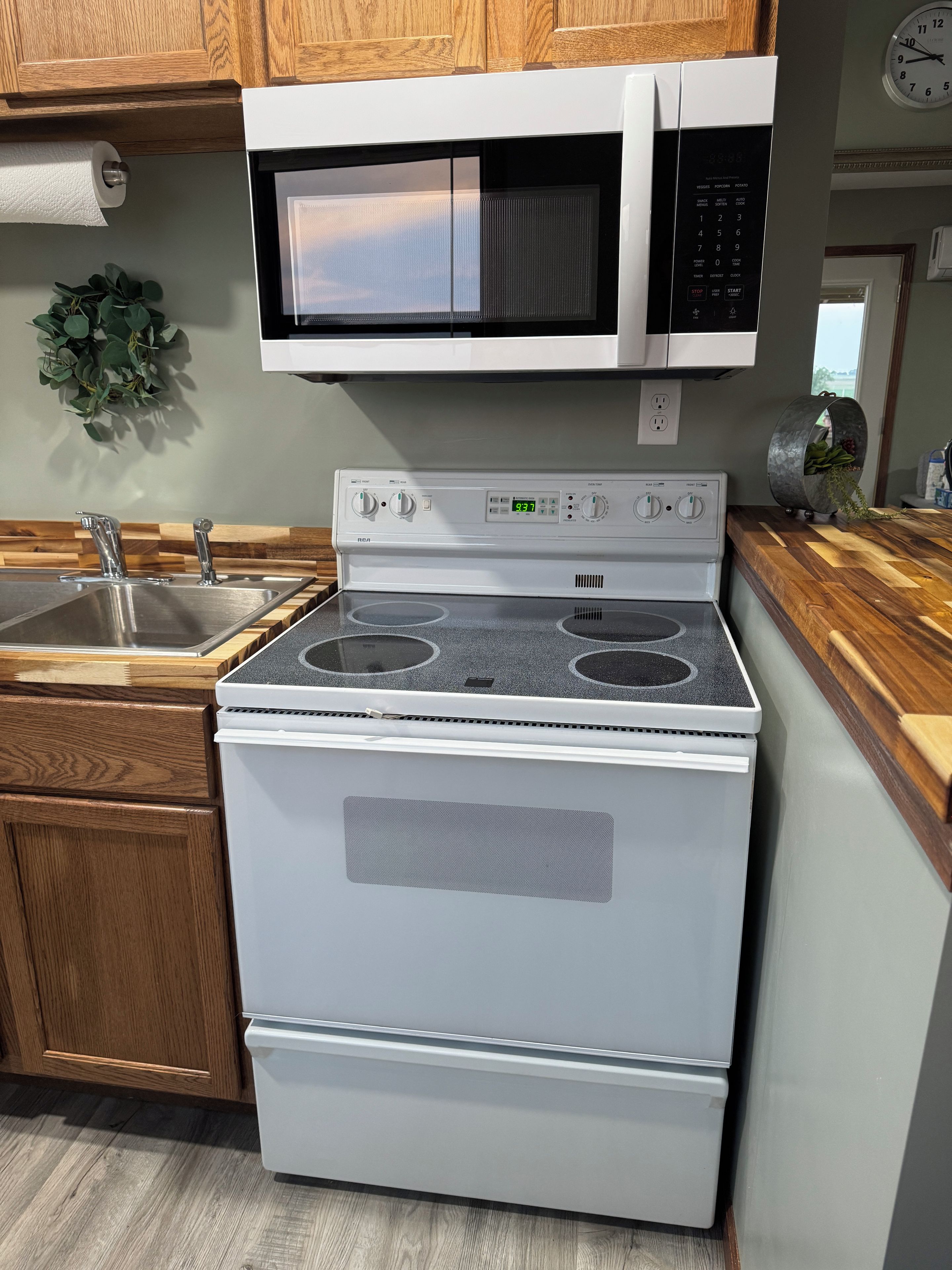 A kitchen with a stove, microwave, and wooden cabinets.