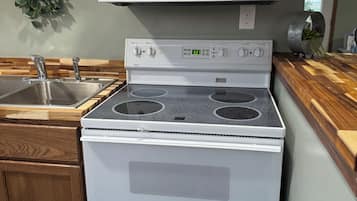 A kitchen with a stove, microwave, and wooden cabinets.