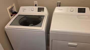 Two white Whirlpool front-loading washing machines in a laundry room.