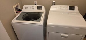 Two white Whirlpool front-loading washing machines in a laundry room.