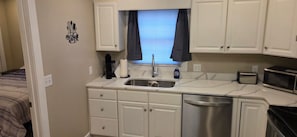 A compact kitchenette with a sink, a coffee maker, a toaster, and a microwave.
