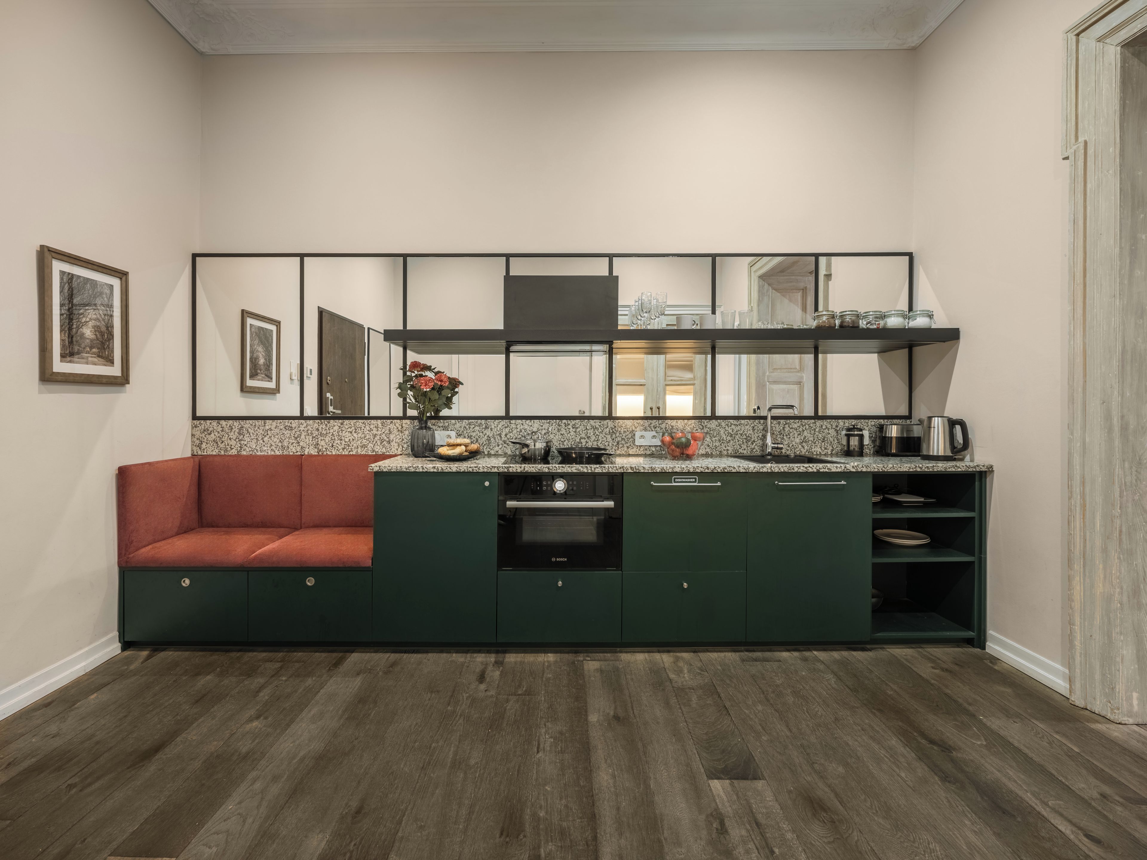 A compact kitchen with a built-in oven, a sink, and a countertop with various kitchen items.