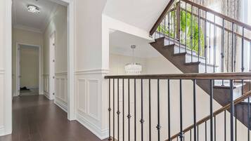 A modern interior with a wooden staircase, white walls, and a hallway leading to another room.