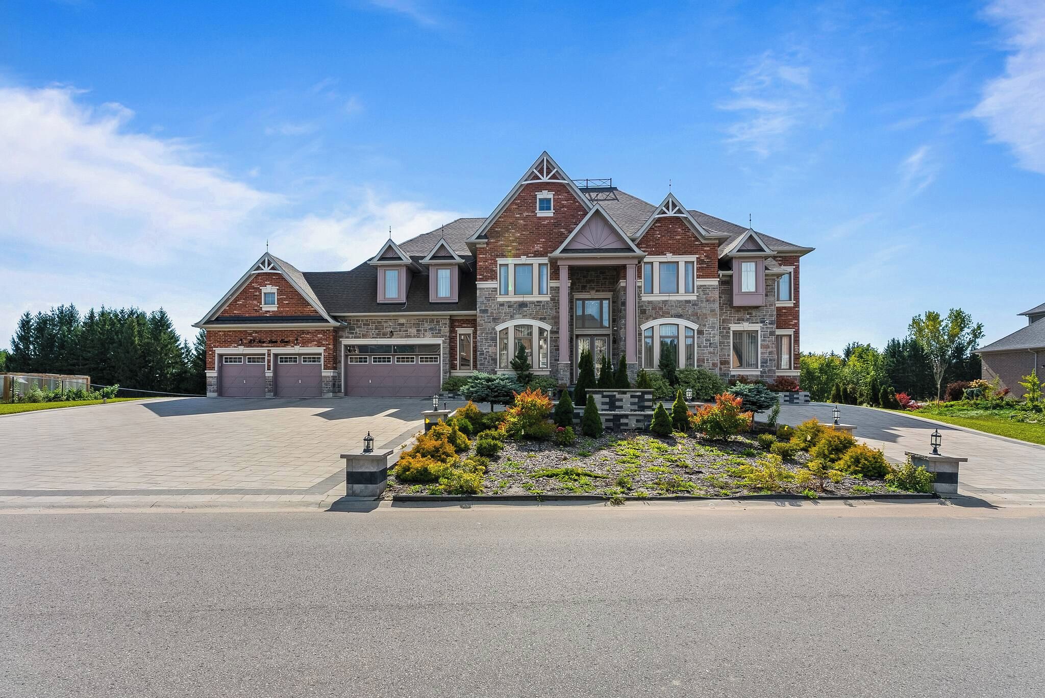 A large two-story house with a garage, a driveway, and a landscaped front yard.