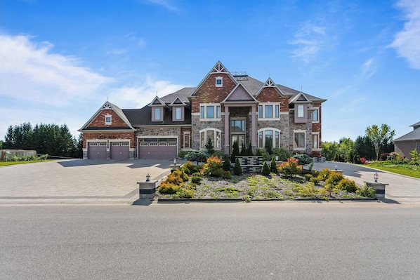 A large two-story house with a garage, a driveway, and a landscaped front yard. - Estate Villa, 6,600 Sqft, 1-acre, 6 Bed, 7 Bath (Whitchurch-Stouffville)