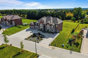 A large, two-story house with a spacious driveway and a well-maintained lawn.