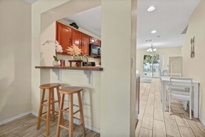 A kitchen with wooden cabinets, a microwave, and two wooden stools. - Family Villa Near Disney, Pool & 2 Suites (Kissimmee)
