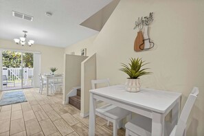Une pièce spacieuse comprenant un coin repas, un escalier et donnant sur l’extérieur.
