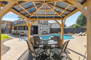 Ett takförsett utomhusområde med en pool, utemöbler och utsikt över en bostadsbyggnad.