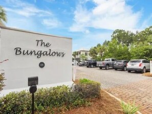 Schild für 'The Bungalows' mit befestigter Auffahrt und geparkten Autos.