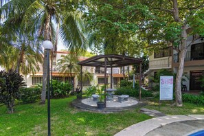 A courtyard with a gazebo, palm trees, and a signboard. - Pool Below, Laundry In, Sleeps 6: Casa Jade (Playas del Coco)