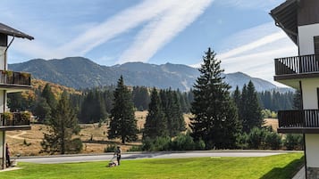 Ein Wohngebiet mit Rasen, einer Person, die mäht, und einem Berg im Hintergrund.