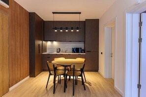 Una cocina moderna con armarios de madera oscura, una mesa de comedor de madera y una lámpara colgante negra.