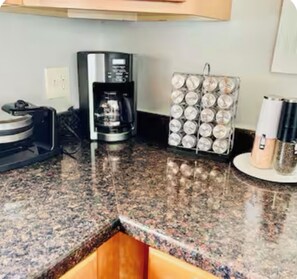 Een keuken met een koffiezetapparaat, een kruidenrek en een magnetron.