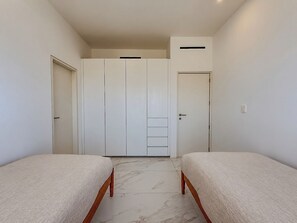 Ein Schlafzimmer mit zwei Betten, einem Kleiderschrank und einer Tür.