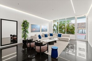 Een moderne woonkamer met een zithoek, salontafel, stoelen en een grote spiegel.
