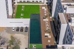 Eine Vogelperspektive eines Hotels mit Swimmingpool, Außenbereich zum Sitzen und einem Parkplatz.