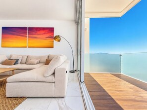 Un salon moderne avec un canapé, une table basse et une grande fenêtre donnant sur un balcon.