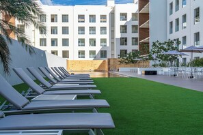 Ein moderner Hotelinnenhof mit Liegestühlen, einem Pool und einer Sitzgelegenheit im Freien.