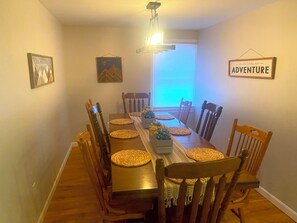 A dining room with a wooden table and chairs, a chandelier, and a window with blinds. - Lovely 5-bedroom / 2 Bathroom / Pet-friendly (McHenry)