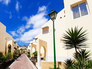 A pathway lined with arches and potted plants, leading to a building with a flat roof and a satellite dish. - MAREVERDE WIFI FREE & POOL VIEW (Costa Adeje)