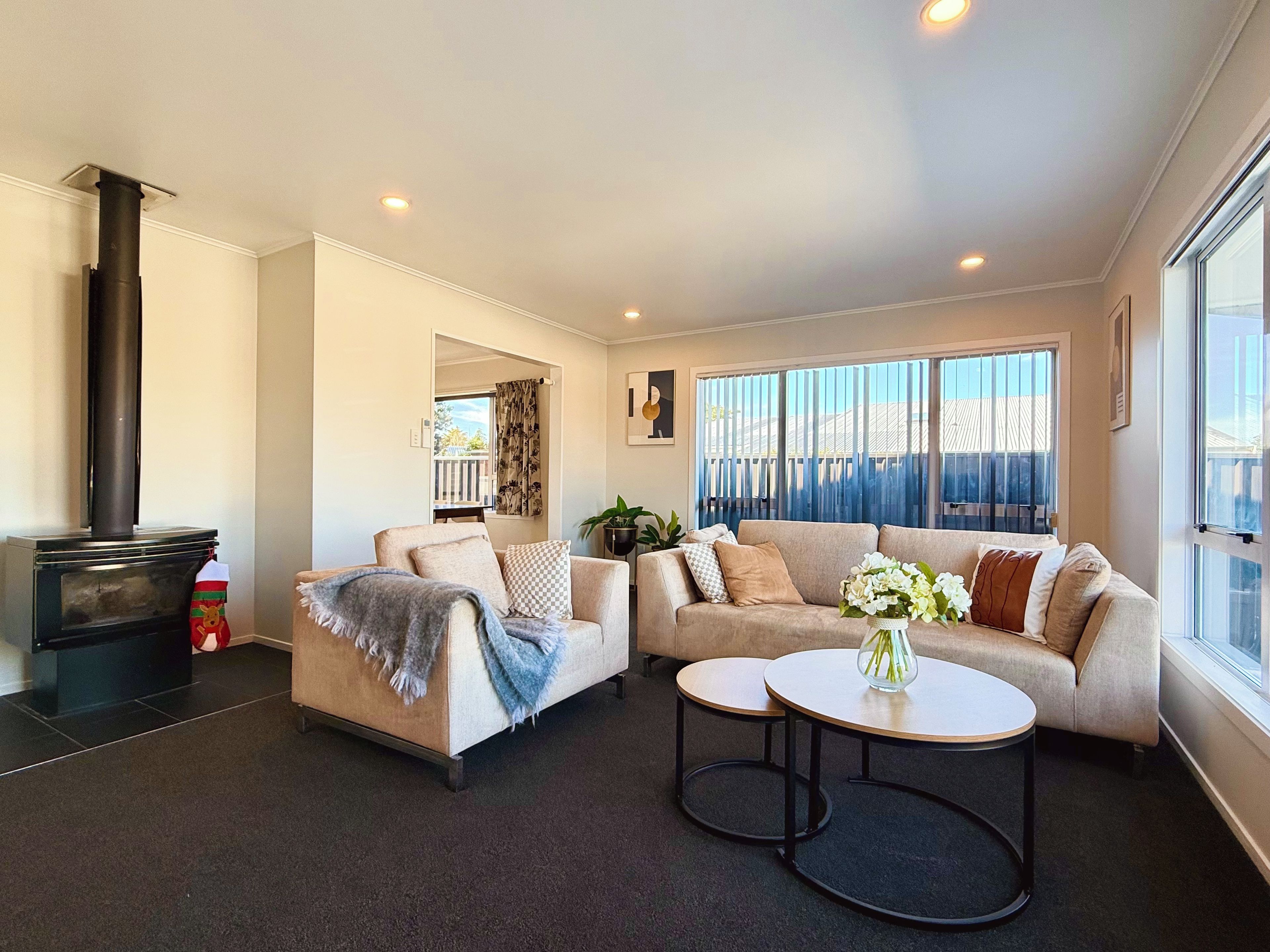 A modern living room with a fireplace, a sofa set, a coffee table, and a view through large windows.