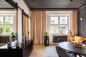 A modern hotel room with a dining area, large windows, and a view of the cityscape. - Eclectic 2-bed apartment by Fragola (Kraków)