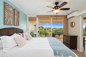 A bedroom with a bed, a ceiling fan, a view through a sliding glass door to an outdoor patio, and a dresser. - Island Escape | Steps to Sand + Pools (Kihei)