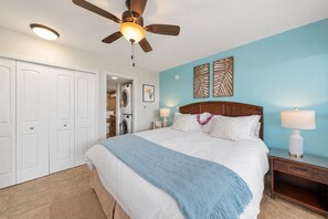 Un dormitorio con cama, ventilador de techo, mesita de noche y lámpara de pared.