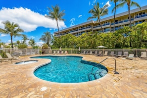 A swimming pool with lounge chairs and palm trees, surrounded by a building with balconies. - Tropical Studio Escape | Walk to Beach (Kihei)