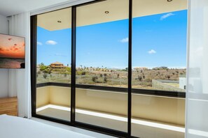 A room with a large sliding glass door leading to a balcony with a view of a desert landscape and buildings. - NEW 4BR Luxury Villa | Pool | Tierra del Sol - Catalina 34 by Bocobay (Noord)