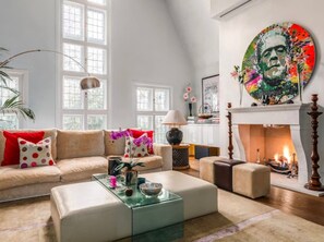 A spacious living room with a fireplace, a sofa set, a coffee table, and a large window. - The Chelsea Town House (London)
