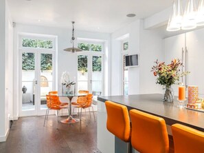 A modern kitchen with a bar area, featuring a dining set and a vase with flowers. - The Chelsea Town House (London)