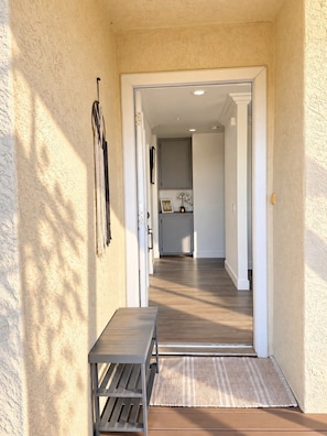 A hallway with a wooden bench, a rug, and a door leading to a room with a mirror and a cabinet. - Panoramic Views, Outdoor Kitchen & Spacious 3BR Home (Spring Valley)