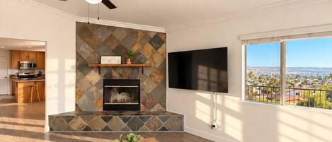 A modern living room with a fireplace, a television, and a view of a cityscape.
