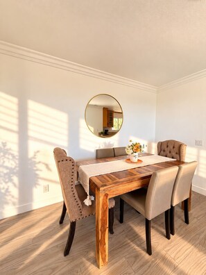 A dining area with a wooden table, six chairs, a round mirror, and a vase with flowers. - Panoramic Views, Outdoor Kitchen & Spacious 3BR Home (Spring Valley)