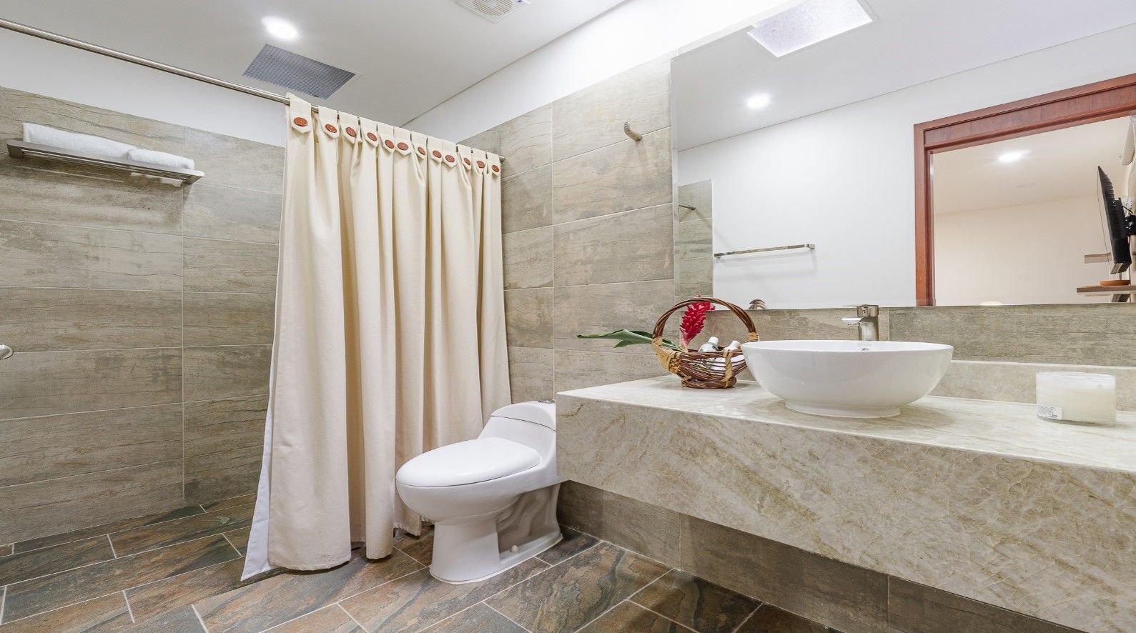 A modern bathroom with a shower, toilet, and a large sink with a vessel basin.