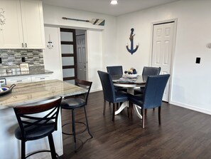 A dining area with a marble island, dark wood flooring, and a white door. - Coastal Cutie! Freshly Remodeled Retreat Close to Beaches/Shopping/Restaurants (Venice)