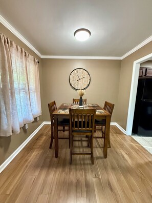 A dining area with a round table, four chairs, a wall clock, and a ceiling light. - Peaceful 3-BR House in Vibrant Memphis (Memphis)