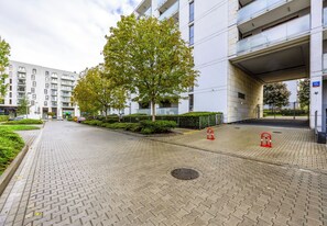 A paved walkway with a tree and bushes, a building with balconies, and a gated entrance. - Zielony Żoliborz Urban Apartment (Warszawa)