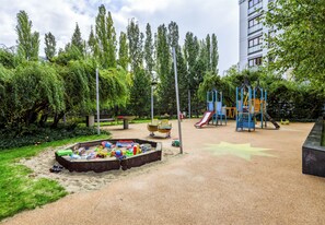Ein Spielplatz mit Sandkasten, Klettergerüsten und einer Rutsche.