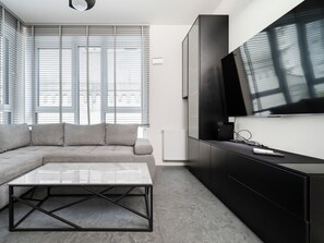 Ein modernes Wohnzimmer mit einer Eckcouch, einem Glastisch, einer schwarzen Unterhaltungseinheit und einem großen Flachbildfernseher.